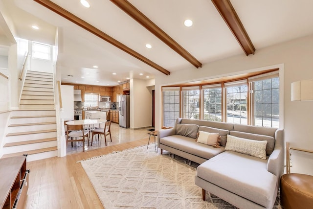 living room with recessed lighting, beamed ceiling, light wood-style flooring, and stairway