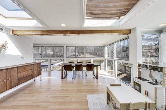 dining room featuring light wood-type flooring, beam ceiling, visible vents, and a skylight