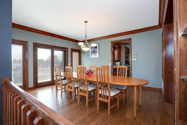 dining space with crown molding, wood finished floors, and baseboards