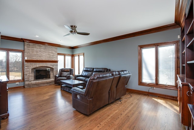 living area with plenty of natural light, light wood-style floors, a brick fireplace, and ceiling fan