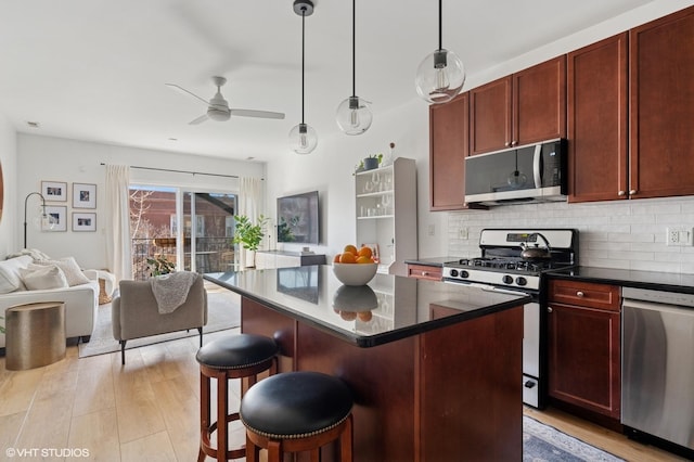 kitchen with light wood-type flooring, a ceiling fan, stainless steel appliances, reddish brown cabinets, and decorative backsplash