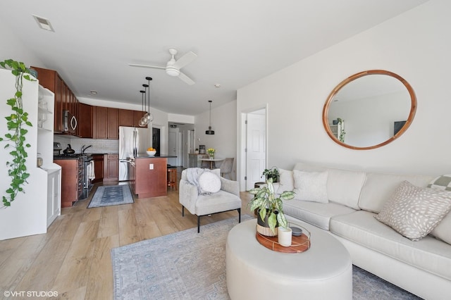 living area featuring light wood-style flooring, a ceiling fan, and visible vents