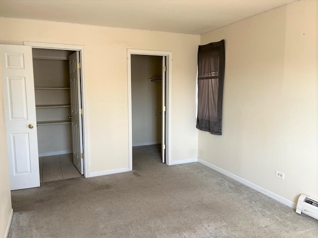 unfurnished bedroom with a walk in closet, carpet flooring, and baseboards