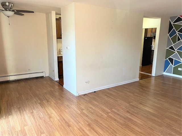 spare room featuring light wood-style flooring, baseboards, a baseboard heating unit, and a ceiling fan