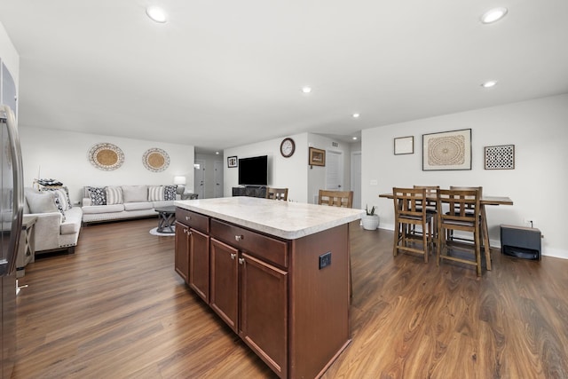 kitchen featuring dark wood finished floors, open floor plan, a kitchen island, and light countertops