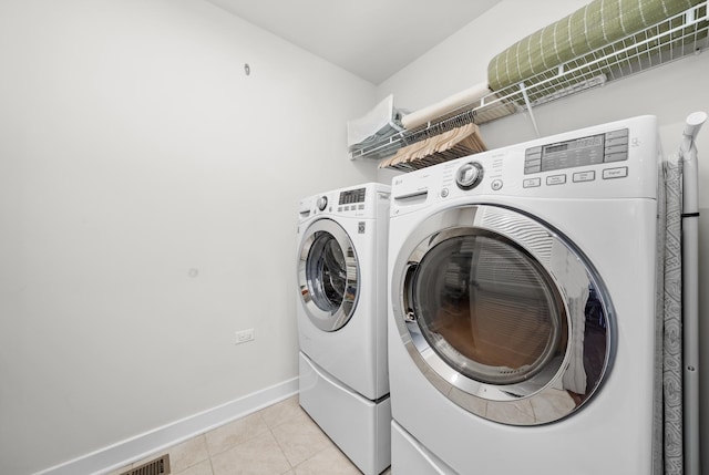 laundry room with laundry area, light tile patterned floors, separate washer and dryer, and baseboards