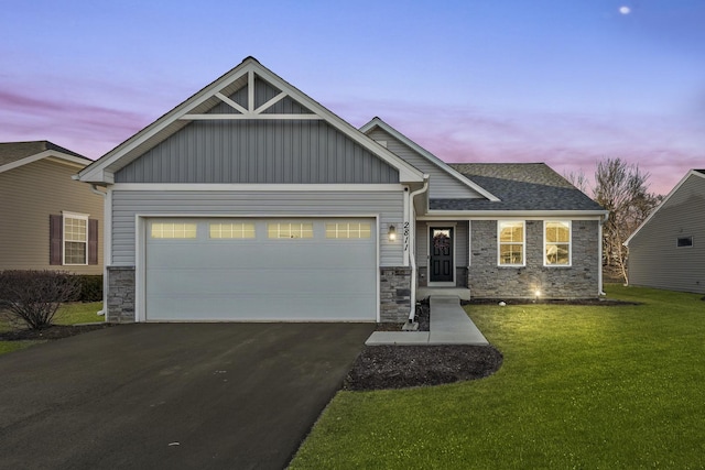 craftsman inspired home with driveway, stone siding, a yard, board and batten siding, and an attached garage