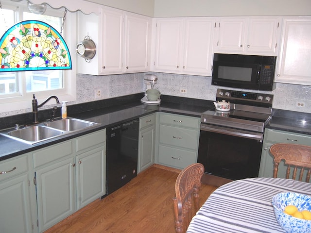 kitchen with black appliances, a sink, backsplash, wood finished floors, and white cabinetry