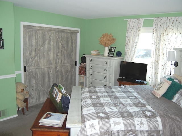 bedroom with visible vents, a barn door, a closet, and carpet flooring