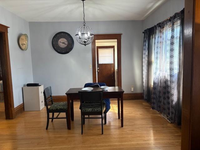 dining area with a chandelier, light wood-style flooring, and baseboards