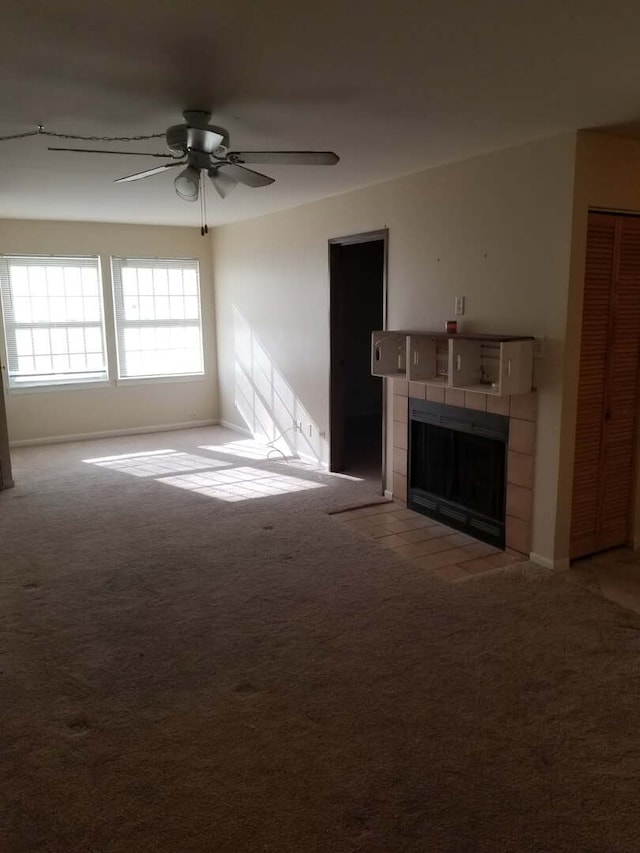 unfurnished living room with light carpet, a tile fireplace, baseboards, and ceiling fan