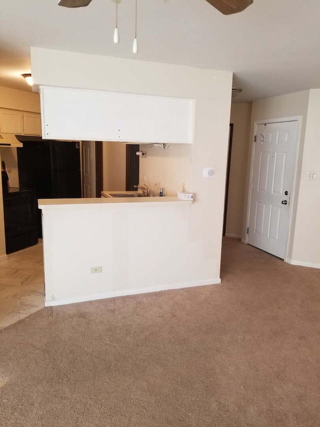 interior space featuring light colored carpet, baseboards, and a ceiling fan