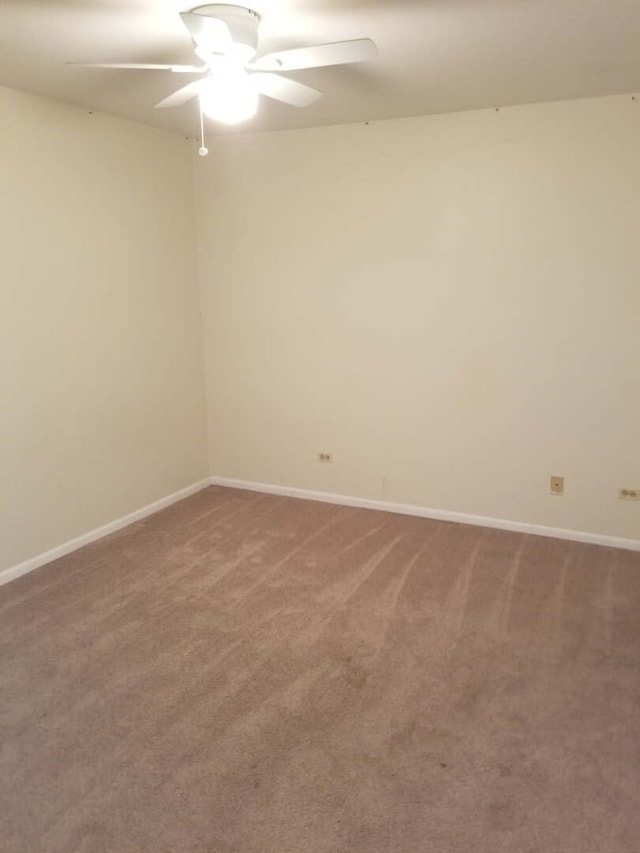 empty room featuring carpet flooring, baseboards, and a ceiling fan