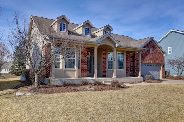 new england style home with driveway, brick siding, a porch, and a front lawn