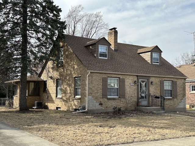 new england style home featuring a shingled roof, brick siding, central AC, and a chimney