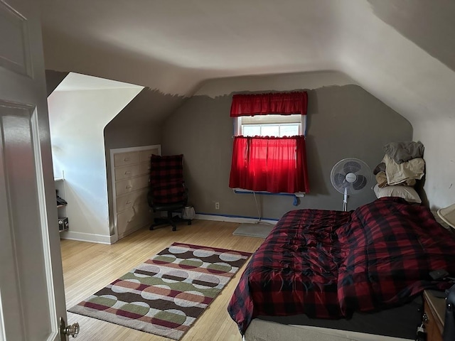 bedroom with baseboards, wood finished floors, and vaulted ceiling