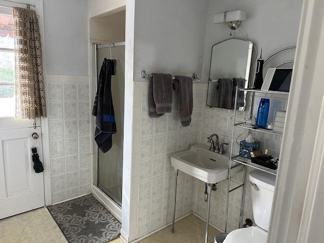 bathroom with tile walls, toilet, and a shower stall