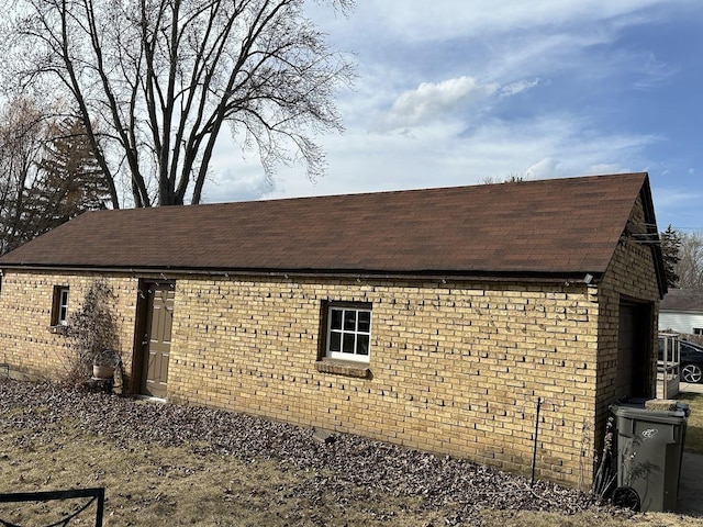 view of home's exterior with brick siding and a shingled roof