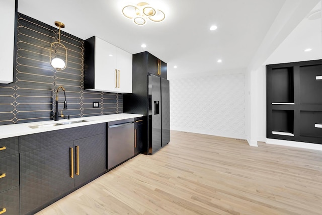 kitchen with refrigerator with ice dispenser, a sink, stainless steel dishwasher, light wood finished floors, and light countertops