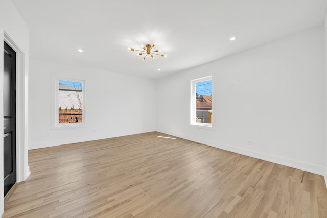 spare room featuring recessed lighting, baseboards, a notable chandelier, and light wood finished floors