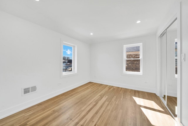 unfurnished bedroom with light wood-type flooring, multiple windows, baseboards, and recessed lighting