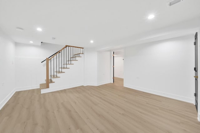 finished basement with light wood finished floors, visible vents, recessed lighting, and stairs