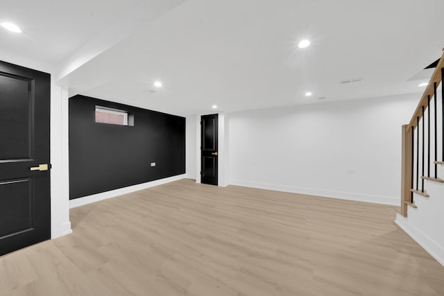 finished below grade area featuring light wood-type flooring, visible vents, recessed lighting, baseboards, and stairs