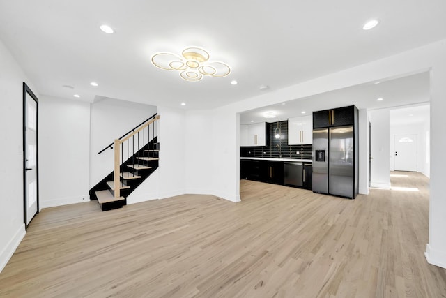 kitchen with dark cabinetry, recessed lighting, stainless steel appliances, light wood-style floors, and tasteful backsplash