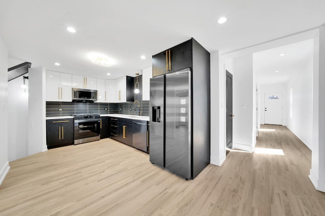 kitchen with tasteful backsplash, light wood finished floors, light countertops, white cabinets, and stainless steel appliances