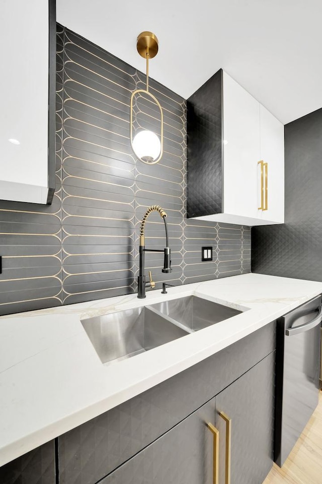 kitchen featuring dishwasher, modern cabinets, tasteful backsplash, and a sink