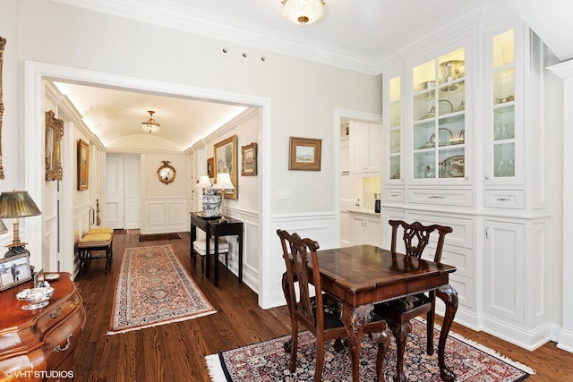 dining room with a decorative wall, a wainscoted wall, dark wood finished floors, and ornamental molding