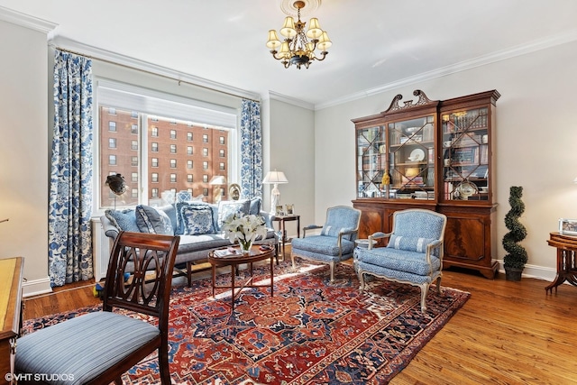 sitting room with a notable chandelier, wood finished floors, baseboards, and ornamental molding