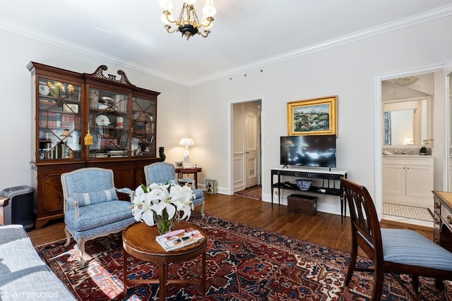 living room with an inviting chandelier, wood finished floors, baseboards, and ornamental molding