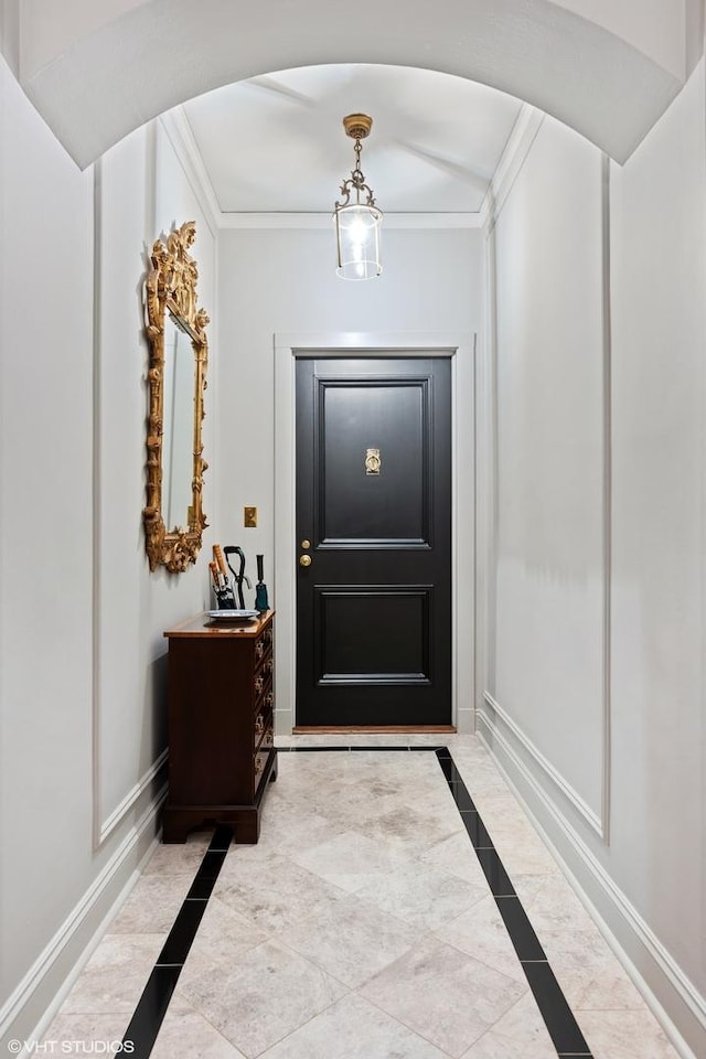 doorway to outside with crown molding, baseboards, and arched walkways