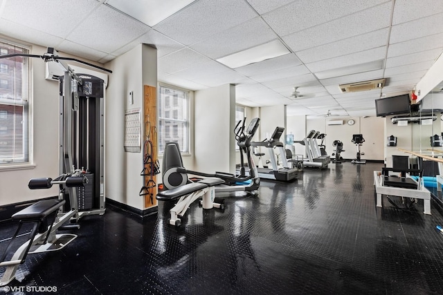 exercise room with plenty of natural light, a paneled ceiling, and baseboards