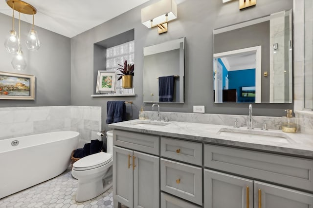 bathroom with a sink, a freestanding bath, double vanity, and toilet