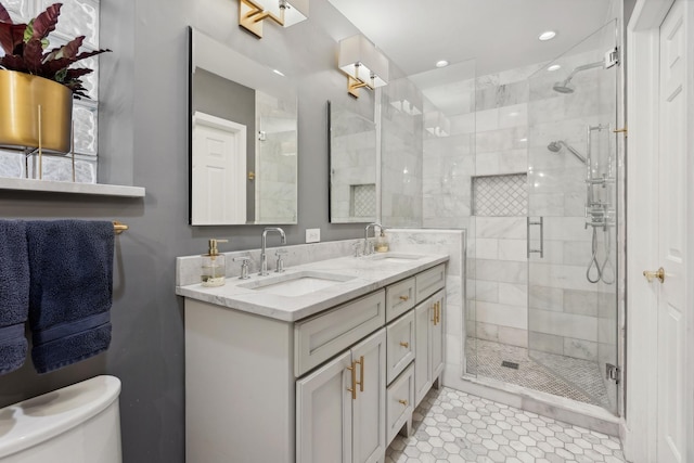 bathroom featuring a shower stall, toilet, double vanity, and a sink