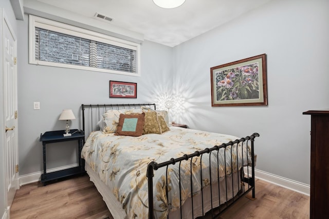 bedroom with visible vents, baseboards, and wood finished floors