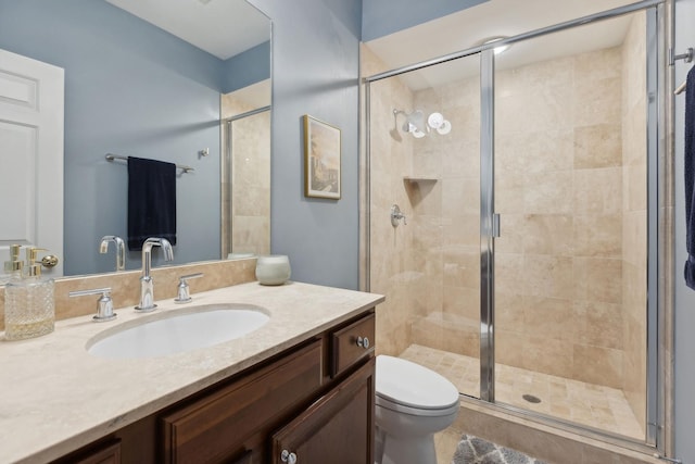 full bathroom featuring toilet, a stall shower, and vanity