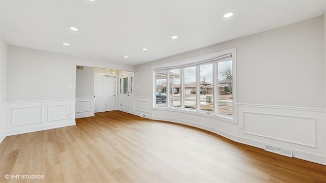 unfurnished room with recessed lighting, visible vents, a wainscoted wall, and light wood-style flooring