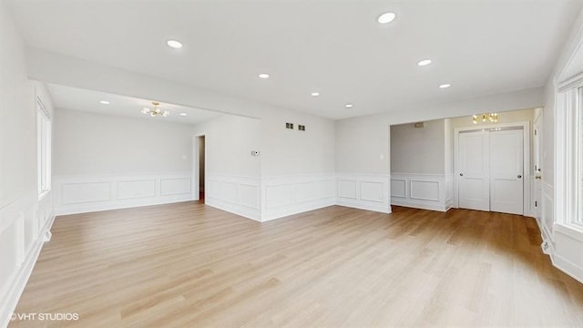 unfurnished room with a chandelier, a decorative wall, recessed lighting, and light wood-type flooring