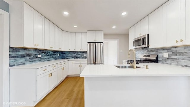 kitchen with white cabinets, a peninsula, stainless steel appliances, and light countertops