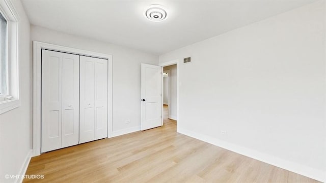 unfurnished bedroom with wood finished floors, visible vents, and baseboards