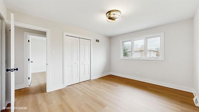 unfurnished bedroom featuring a closet, baseboards, visible vents, and light wood finished floors