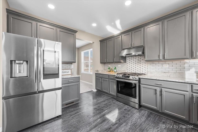 kitchen featuring gray cabinets, dark wood-type flooring, under cabinet range hood, appliances with stainless steel finishes, and backsplash