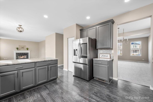 kitchen featuring dark wood-style floors, baseboards, gray cabinets, a tile fireplace, and stainless steel fridge