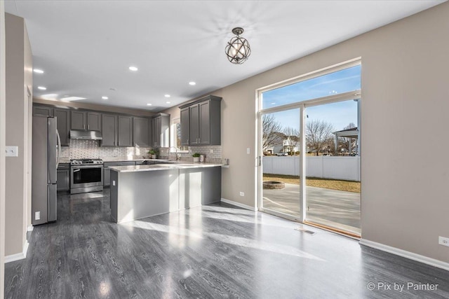 kitchen with under cabinet range hood, decorative backsplash, a healthy amount of sunlight, and appliances with stainless steel finishes