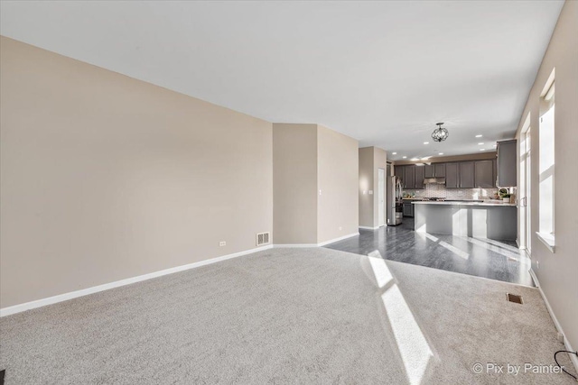 unfurnished living room featuring recessed lighting, baseboards, visible vents, and dark colored carpet