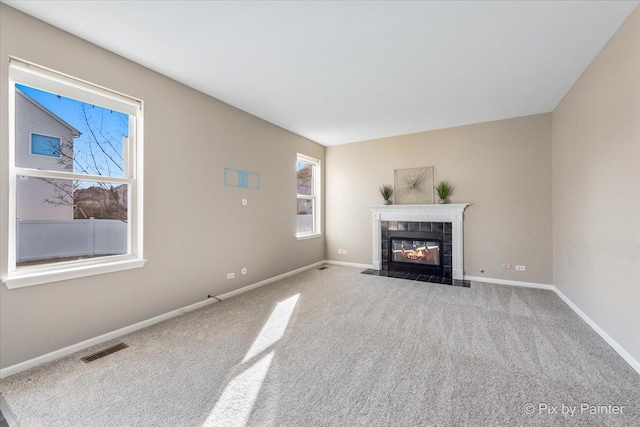 unfurnished living room featuring baseboards, visible vents, carpet floors, and a tile fireplace