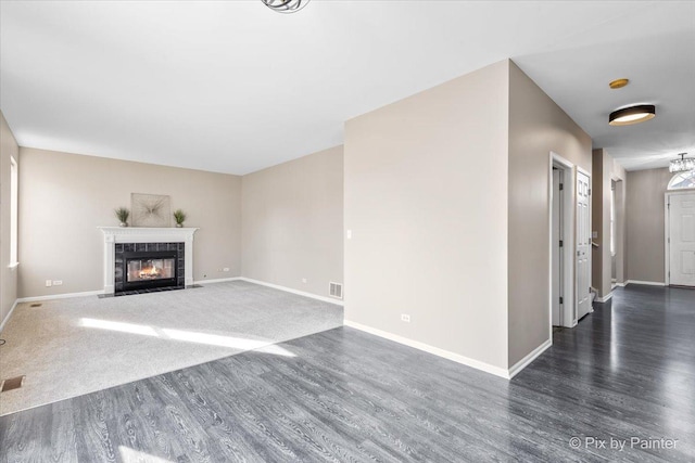 unfurnished living room with wood finished floors, a fireplace, visible vents, and baseboards